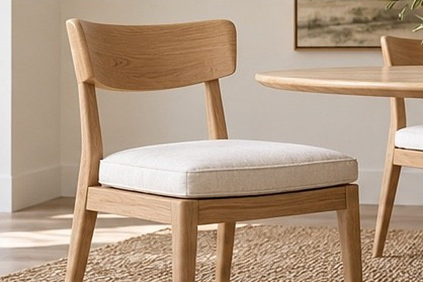 Light oak dining chair with a removable ivory seat cushion beside a round table